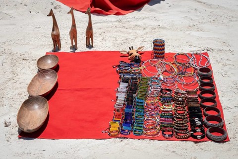 Traditional African handmade jewelry, beaded bracelets, wooden bowls, and giraffe figurines