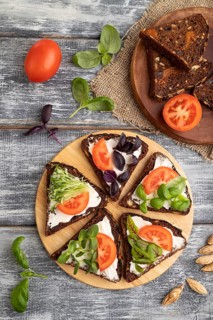Grain rye bread sandwiches with cream cheese, tomatoes and microgreen on gray wooden background and
