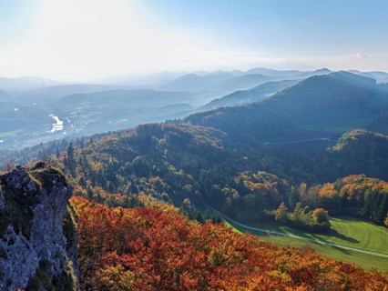 View of an autumnal forest from the Gisliflue, behind the Jurassic foothills with the Wasserfluh,