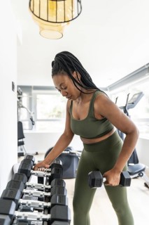 Businesswoman is picking up dumbbells in a hotel gym, maintaining her fitness routine while