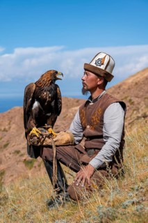 Traditional Kyrgyz eagle hunter with eagle in the mountains, near Kysyl-Suu, Kyrgyzstan