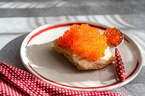 Top view of healthy organic red caviar from trout fish served on a toasted bread slice, placed on a