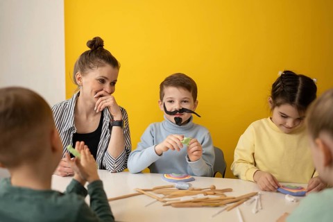 Children engaged in a lively art class, modeling clay, wearing playful costumes. They are enjoying