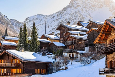 Snow-covered old farmhouses, large wooden cross, historic town center, Grimentz, Val d'Anniviers,