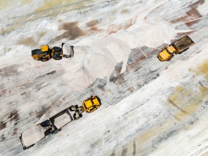 Excavator and lorries and at a harvesting pan of the Walvis Bay Salt works. Aerial view. Drone shot