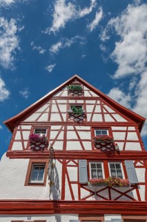 Traditional half-timbered house with flower boxes in front of a blue sky, Annweiler, Palatinate,