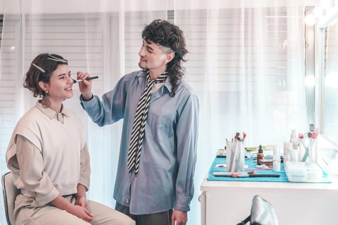 Professional makeup artist applying makeup on a model's face using a brush, working in a beauty