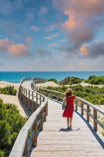 Girl with red dress on the wooden path to Playa Moncayo in Guardamar del Segura next to Torrevieja,