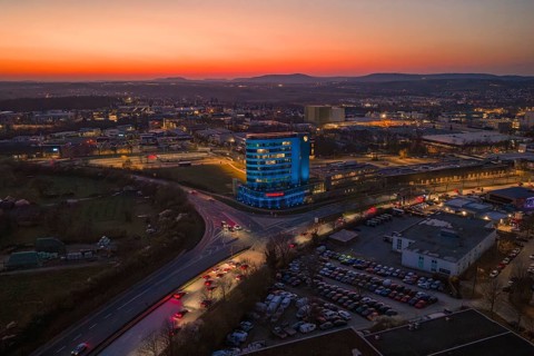 City view in the evening with an illuminated high-rise building and sunset, Porsche, Bietigheim,