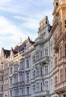 A row of ornate historic buildings with intricate facades and pastel hues under a clear evening sky