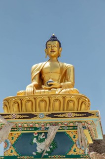 Majestic golden Buddha statue in Charasa, Nubra Valley, India, set against a clear blue sky.