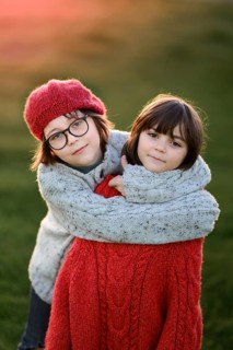 A girl and a boy sibling share a tender hug, enveloped by the warm glow of an autumn sunset,