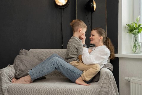 A tender interaction between a mother and her child, sitting on a comfortable sofa. The setting is