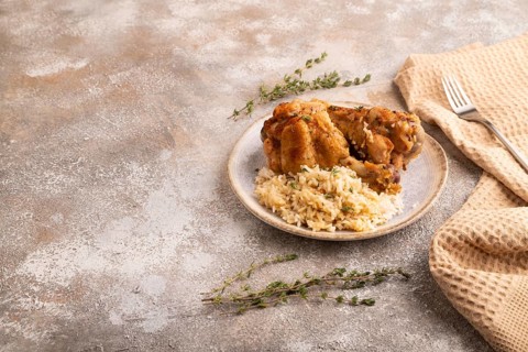 Fried Turkey Wing with spices and rice on brown concrete background and linen textile. side view,