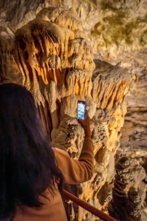 Tourist taking pictures of large stalactites inside postojna cave, a famous tourist attraction in