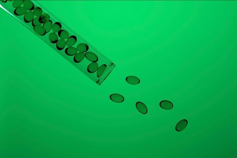 Omega-3 and Vitamin D capsules spill from a clear tilted test tube onto a vibrant green background,