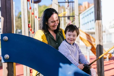 A joyful moment between a mother and her child with Down syndrome playing at the park. The child is