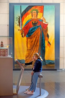 Two woman at a screen in front of the painting of Germania by Philipp Veit, Haus der Geschichte,