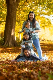 Asian family of four delights in a playful autumn day outdoors, surrounded by colorful falling