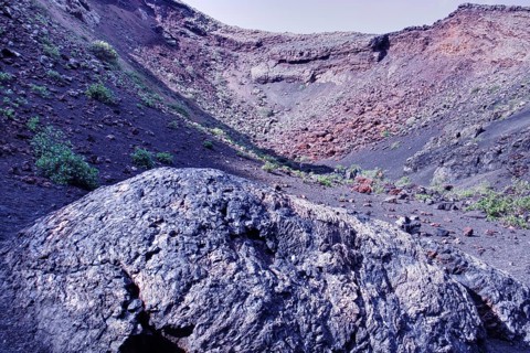 Partial view of Caldera de los Cuervos (El Cuervo volcano) with sparse vegetation and rocks, Tinajo