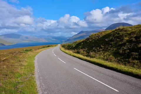 Course of a road through hilly landscape with mountains and blue sky, Little Loch Broom, view
