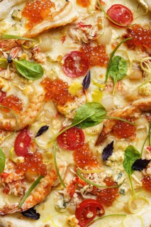 Close up view of a luxurious pizza adorned with succulent shrimp, crab meat, scallops, red caviar,