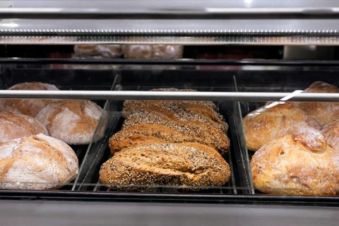 A selection of fresh artisanal bread showcased in a bakery display case at a supermarket. Various