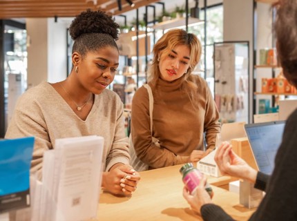 Customers engage with a salesperson in a vibrant cosmetics store, exploring facial products.