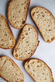 Top view of freshly sliced sourdough bread with a textured, porous interior on a gray background
