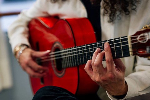 Anonymous Latin man playing red bass guitar in studio