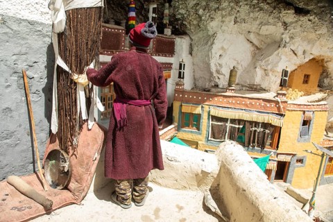 Back view unrecognizable local in traditional attire stands at Phugtal Monastery, Ladakh,