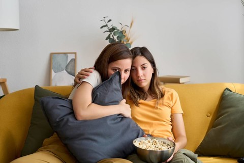 A loving lesbian couple embraces while watching a movie at home They sit closely on a comfortable