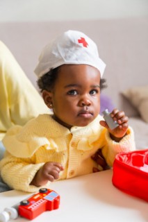 Vertical photo of an adorable african child dressed like doctor playing at home