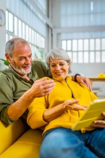 Senior couple reading online news together on the sofa using digital tablet