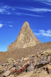 Steeply rising, conical rocks under a vivid, cloudy sky, The landscape of the Ahaggar Mountains in
