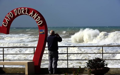 Severe weather waves on the quay wall of Capo D'Orlando. A person photographs the stormy sea on the