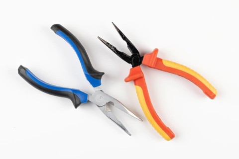 Two pliers with colorful handles, one blue, black others red, orange on a white background