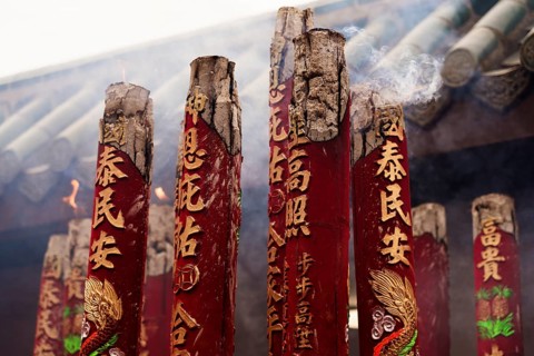 Close-up view of large red incense sticks with detailed carvings, smoldering during the Chinese New