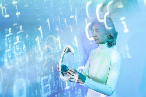 An elderly Asian woman interacts with the virtual metaverse, holding a VR headset. Digital binary
