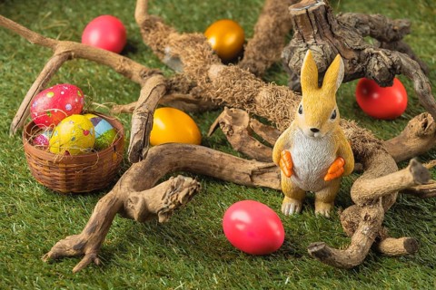 Bunny figure and Easter eggs between roots in the grass