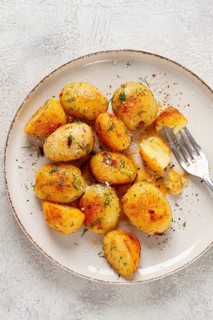 Half-eaten fried new potatoes, with butter and dill, on a white plate, with a fork, at home, no