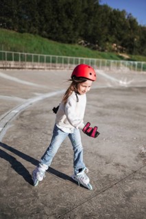 Active young girl roller skating outdoors in a park, wearing helmet and wrist guards for safety