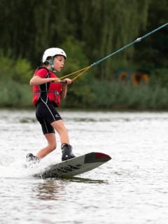 Boy or girl, water sports, wakeboard ride, red life jacket, water skiing in the wake park
