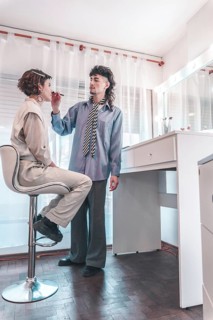 Professional makeup artist carefully applying lipstick on a model sitting on a high chair in a
