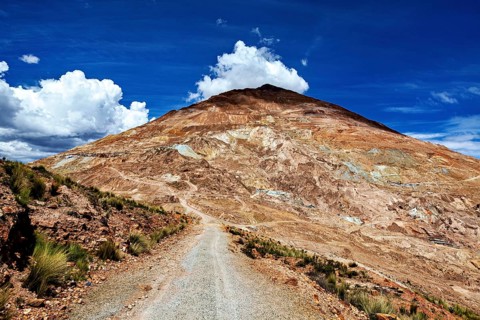 Narrow path leads to a bare mountain under clear blue sky with clouds, The Potosi Silver Mines on