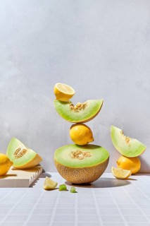 A dynamic arrangement of melons and lemons on a tiled surface. The summer vibes are highlighted by