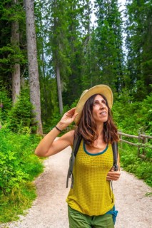 Female tourist enjoying a sunny summer day while hiking along the scenic trails near lake carezza