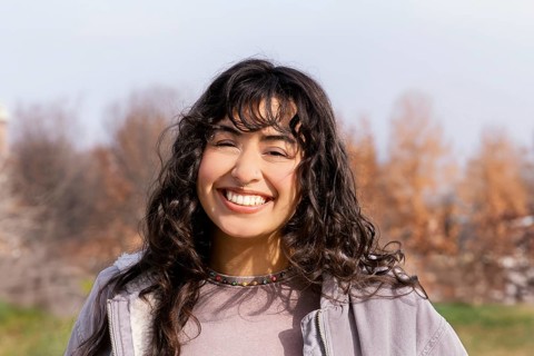 A young Latin woman smiling brightly while enjoying a sunny day outdoors Her cheerful expression