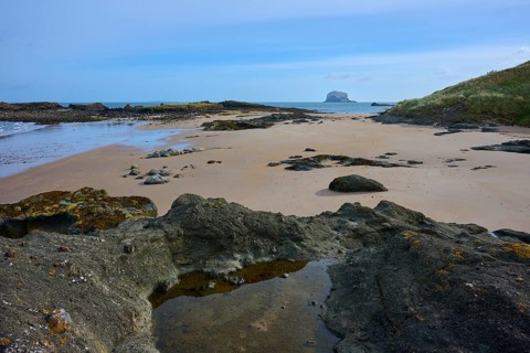 Pristine coastal area with rocks and sand against blue sky and sea, Bass Rock, North Berwick, East