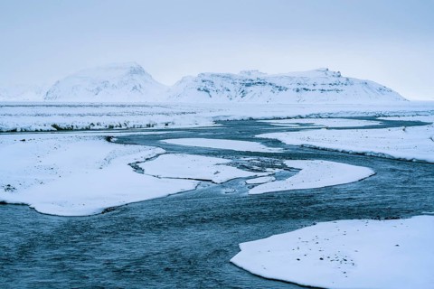 A breathtaking winter landscape of Skaftafell, Iceland, showcasing a serene river meandering